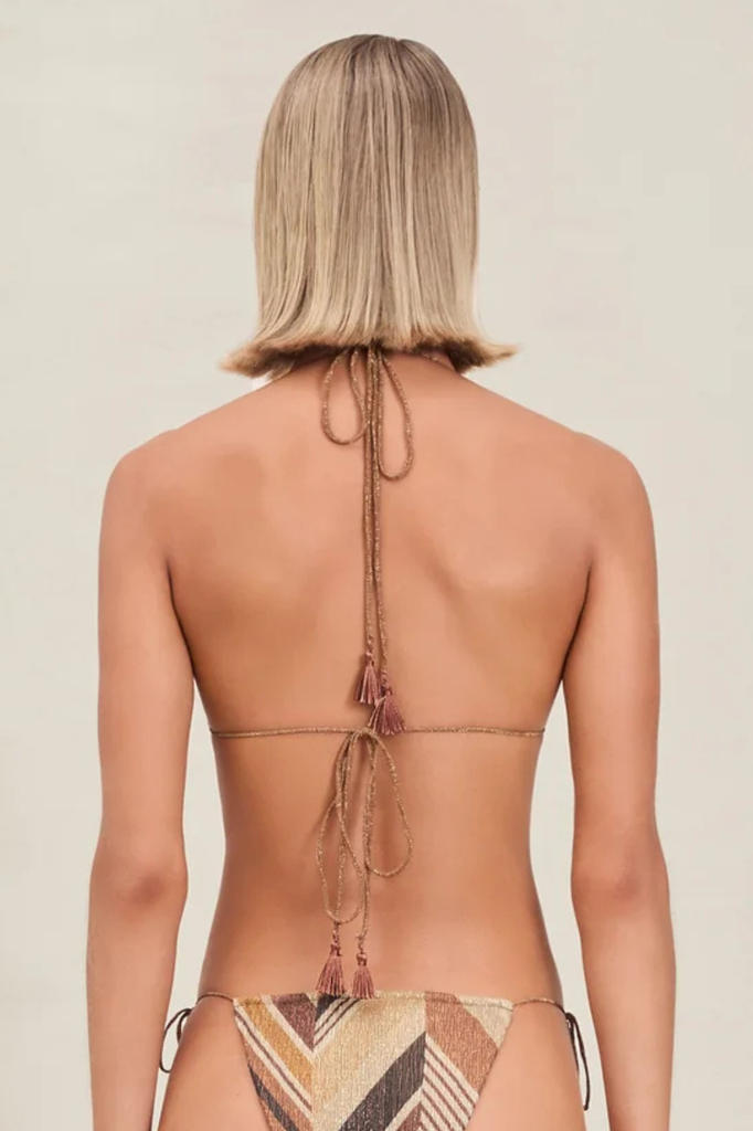Woman wearing a bikini with a unique back design on a beige background