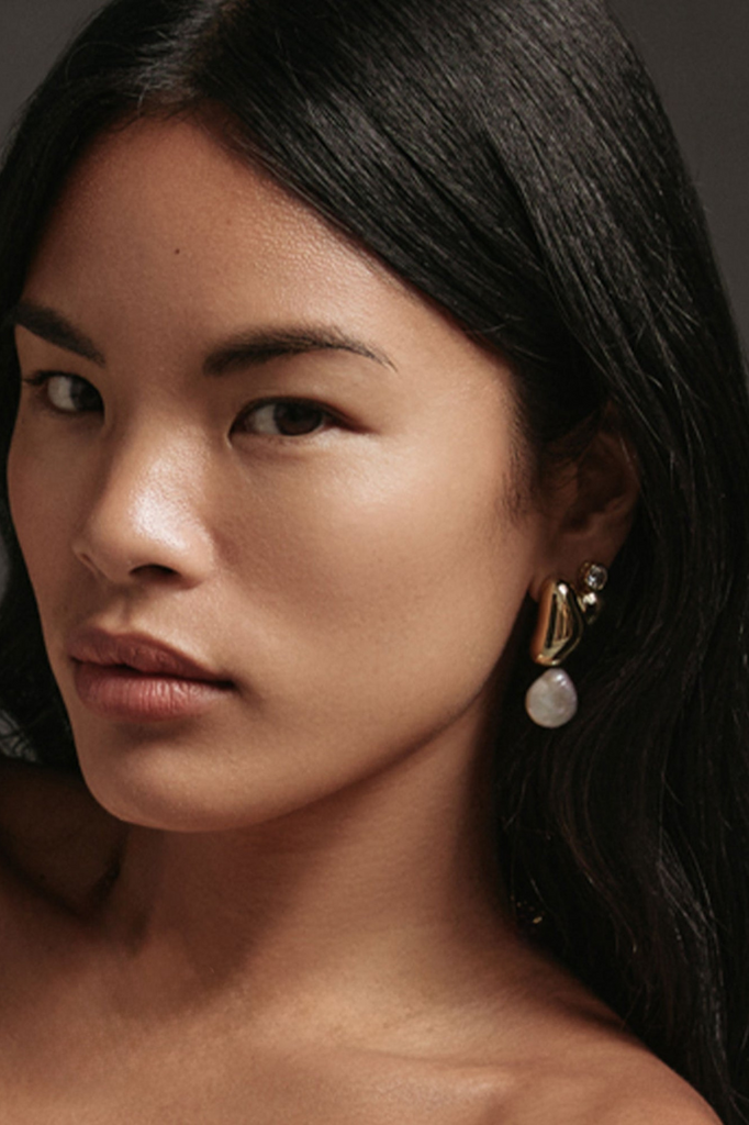 Close-up of a woman wearing earrings with a dark background. Shashi Carter Pearl Drop Earring