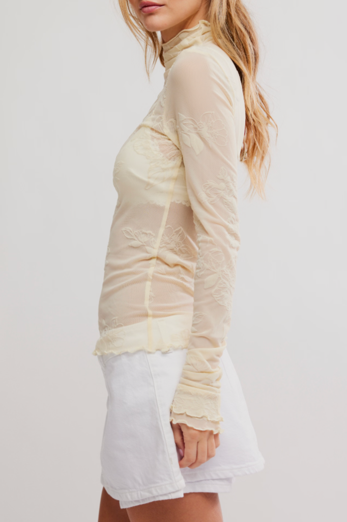 Sheer light yellow-hued long sleeve top with a lettuce trim