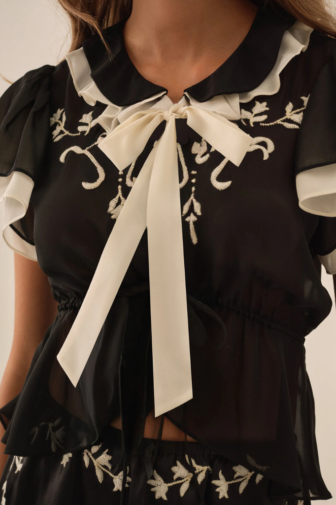 Black satin chiffon blouse with contrasting white trim and embroidery accents