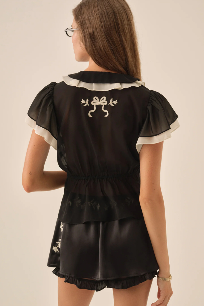 Black satin chiffon blouse with contrasting white trim and embroidery accents